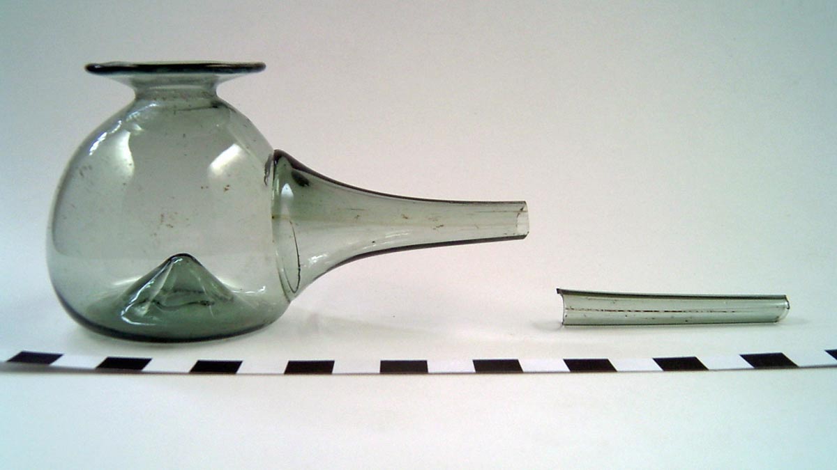 Foto einer Milchpumpe aus grünlichem Waldglas, der lange Hals ist nur als Fragment erhalten